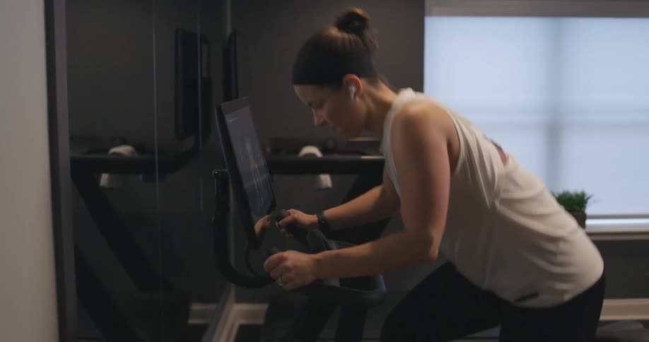 Woman exercises on machine with attached digital screen