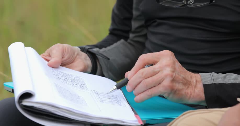 A person is tapping a book and writing in it with a pen