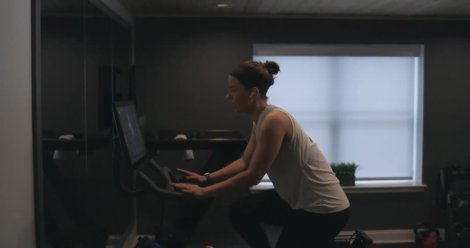 A woman rides a stationary bike at home