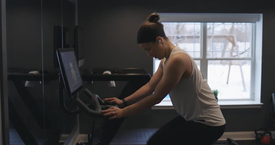 A woman rides an exercise bike at home