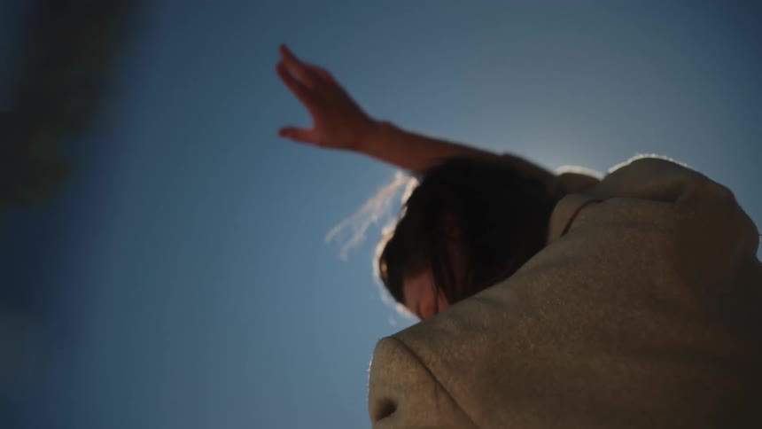 A woman moves her arms up and down while dancing outside