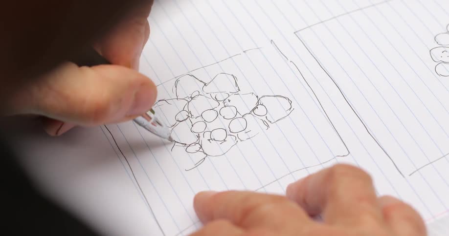 A person is drawing in a notebook with a pen