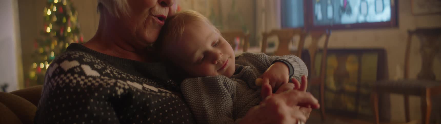 A grandmother is holding and talking to her grandson