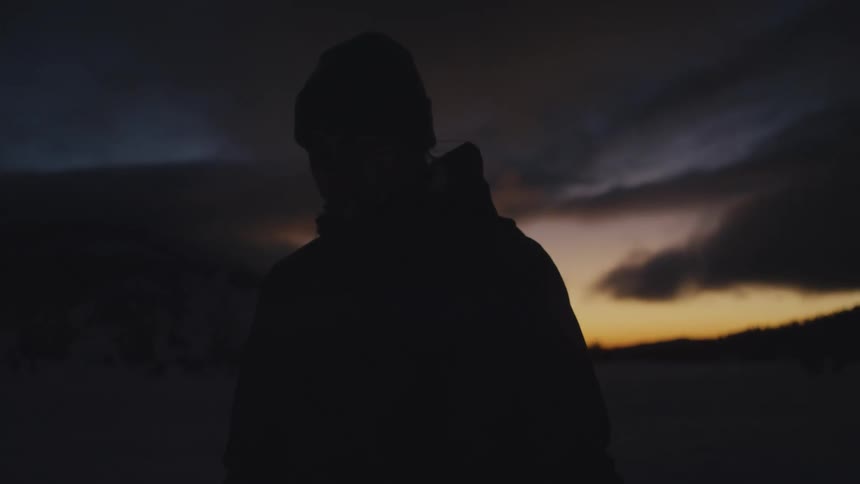 A man wears a hooded sweatshirt and knit beanie for a walk at night