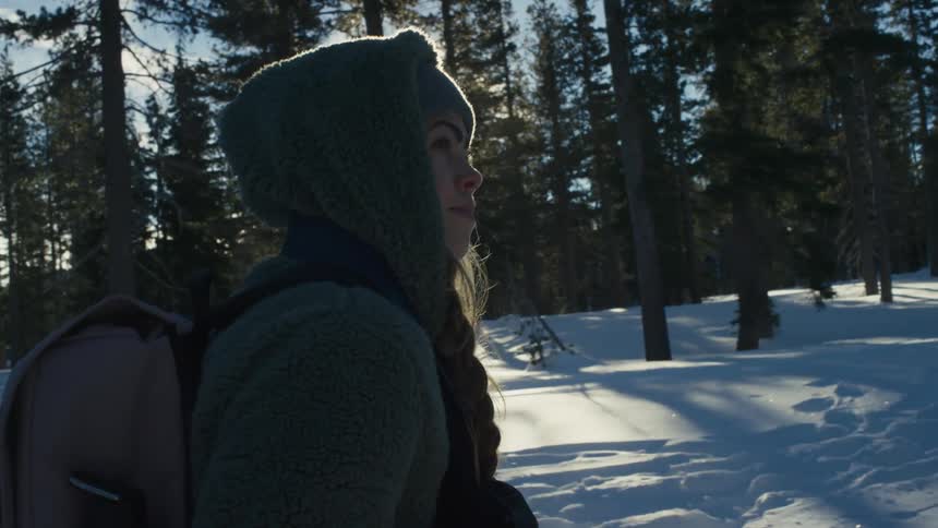 A teenage girl walks through a snowy forest