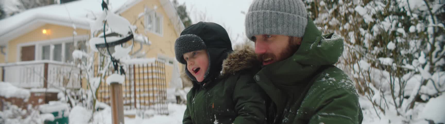Man and woman play in the snow with their young child and have fun throwing snow at each other
