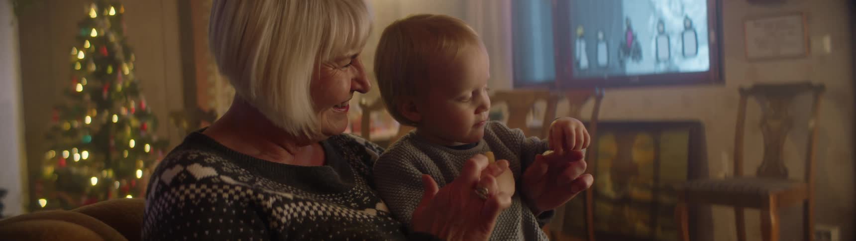 A woman holds her grandson while sitting on the couch