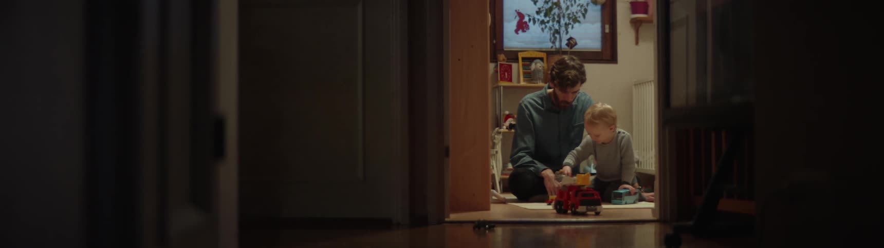Father and son play on floor with a toy fire truck