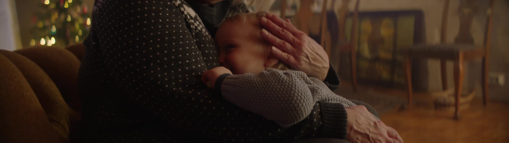 Woman strokes childs head as she sits holding him