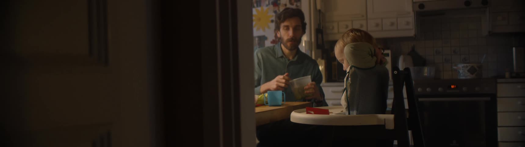Father and son sitting in a highchair eat in the kitchen