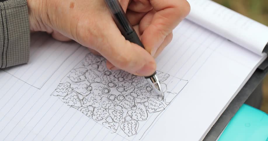 A man is drawing in a notebook with a pen