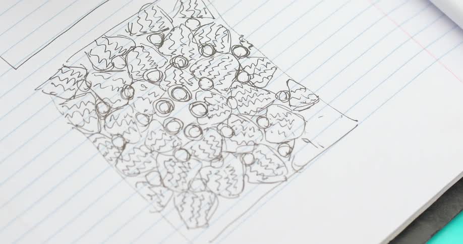 A person is drawing in a notebook with a pen