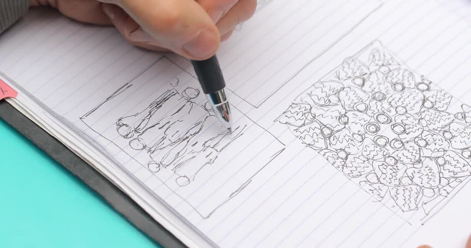 A man draws patterns on notebook paper