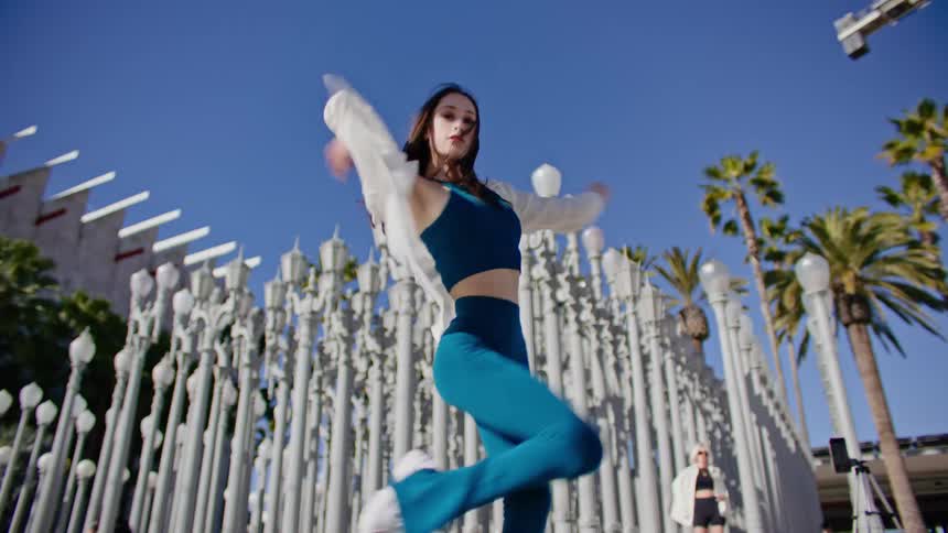 Young woman energetically dancing in front of streetlamp on a park in the city
