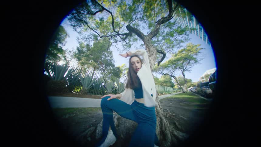 A teenage girl dances outside of a peephole on a house