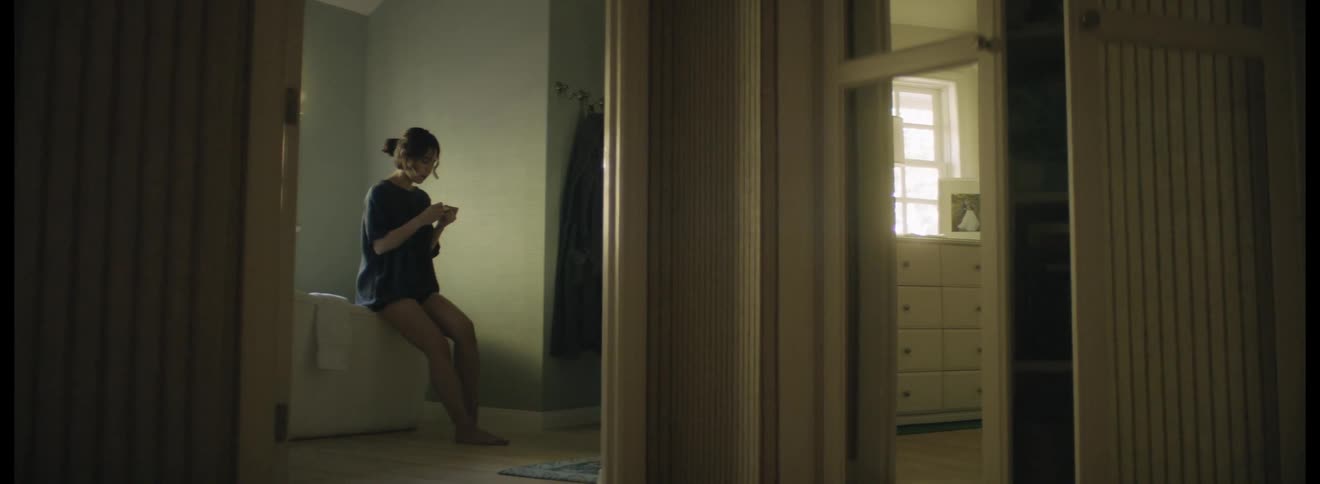 Woman sits on the edge of a bathtub and looks at a pregnancy testing device