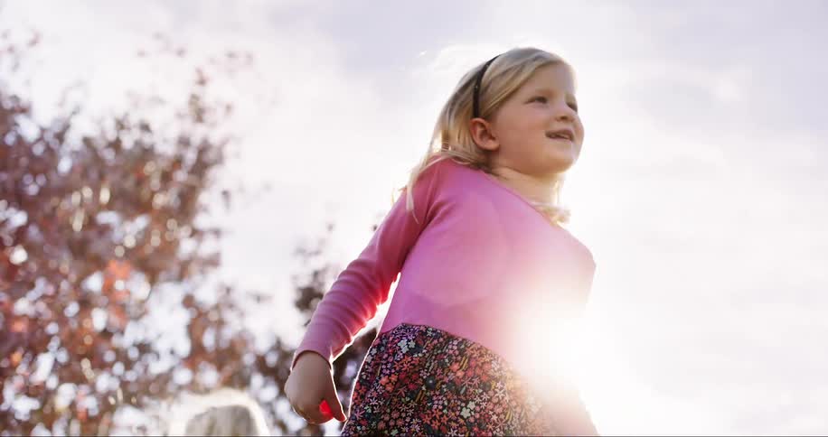 Little blond girl smiles and breathes in the sun on a beautiful fall day