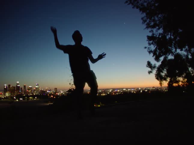 A man is dancing on the hill by the city