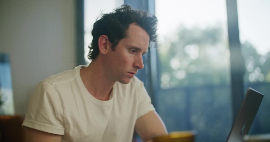 Man sits in front of laptop at home working