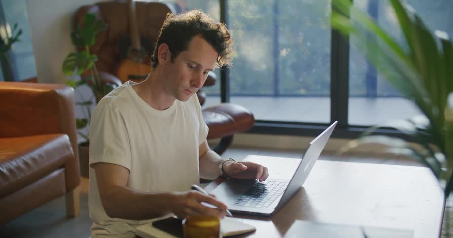 A man is typing on his laptop at home
