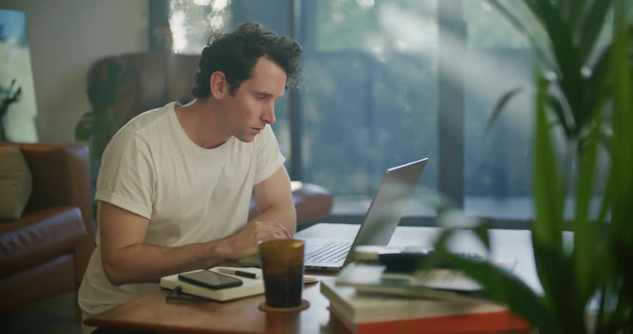 A man is writing notes in his notebook at the desk