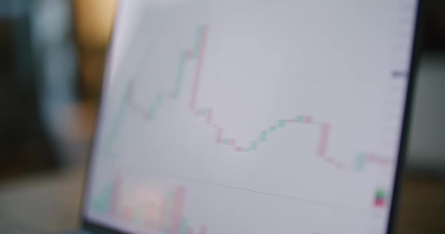 A line graph moves left to right on a laptop screen