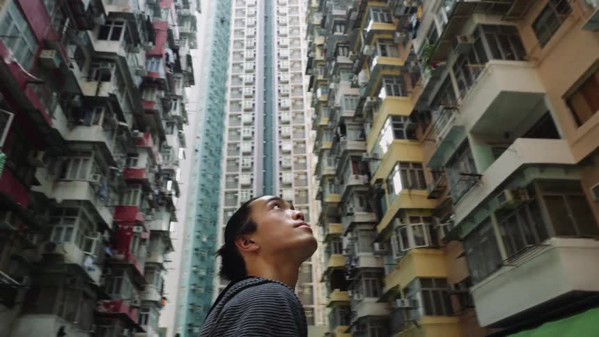 A man is looking up at the tall buildings