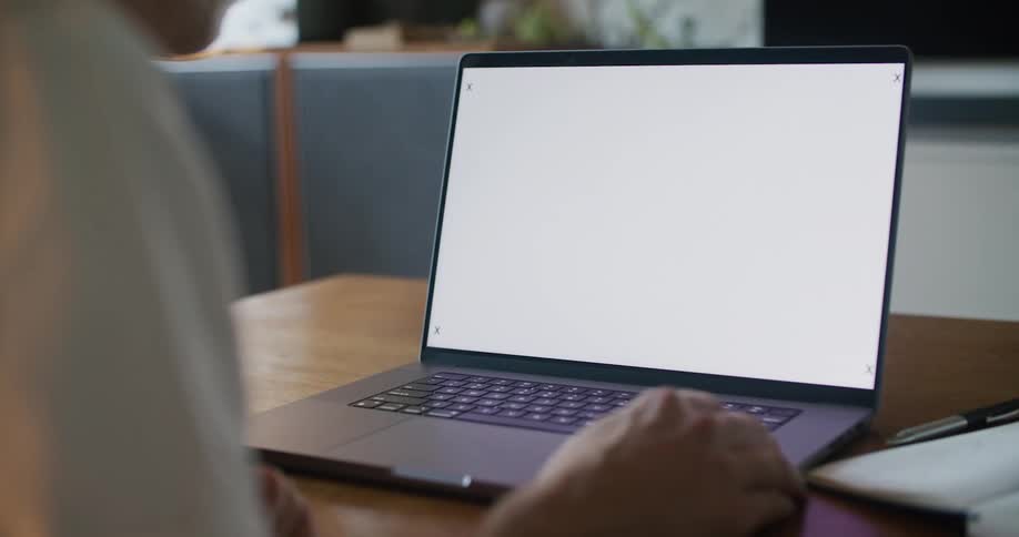 Man working from home uses a laptop with a replaceable screen over the coffee table in the living room