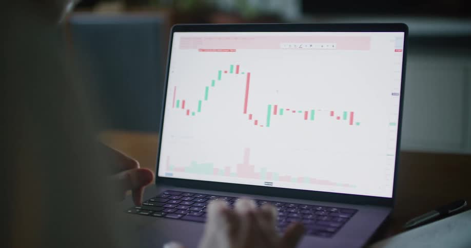 Man analyzing a candlestick chart displayed on his laptop screen