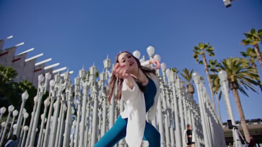 A woman is dancing by a row of lamp posts