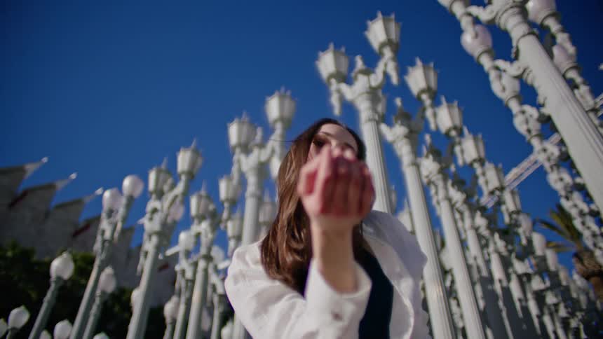 Young woman energetically dancing in front of streetlamps on a park in the city