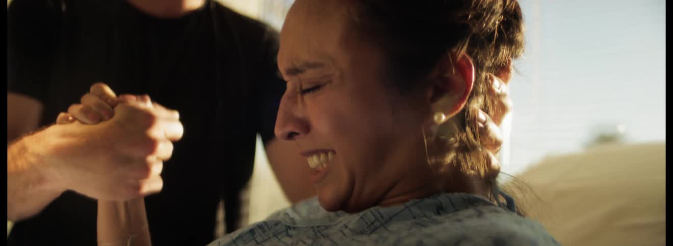Woman in labor pushing during contractions as male holds her hand