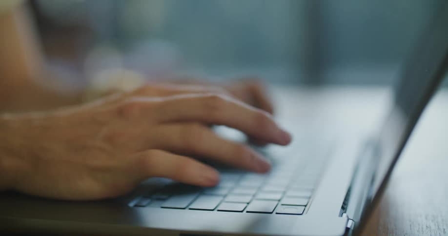 Hands typing energetically on the laptop keyboard over a desk