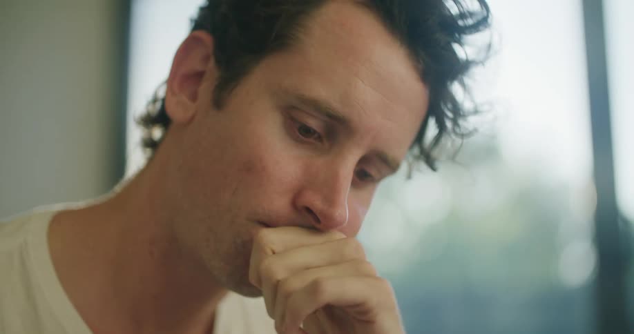 Young man thinking while working on a laptop at home in the morning