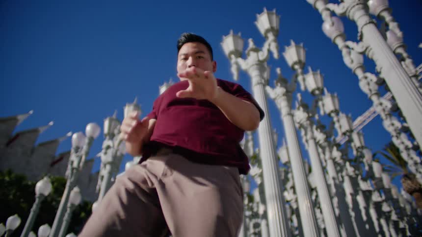 A man dances in front of rows of lamp posts