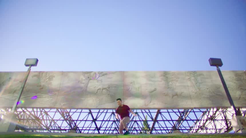 A male dancer performs his moves outside in front of a large mural