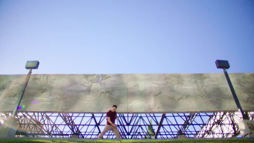 A man dances in front of a billboard