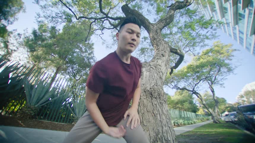 A man dances on the sidewalk in a neighborhood