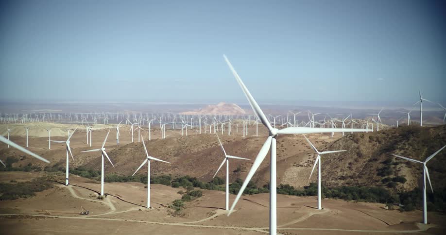 A wind farm with turbines on ridges through the rounded edges of a telescope