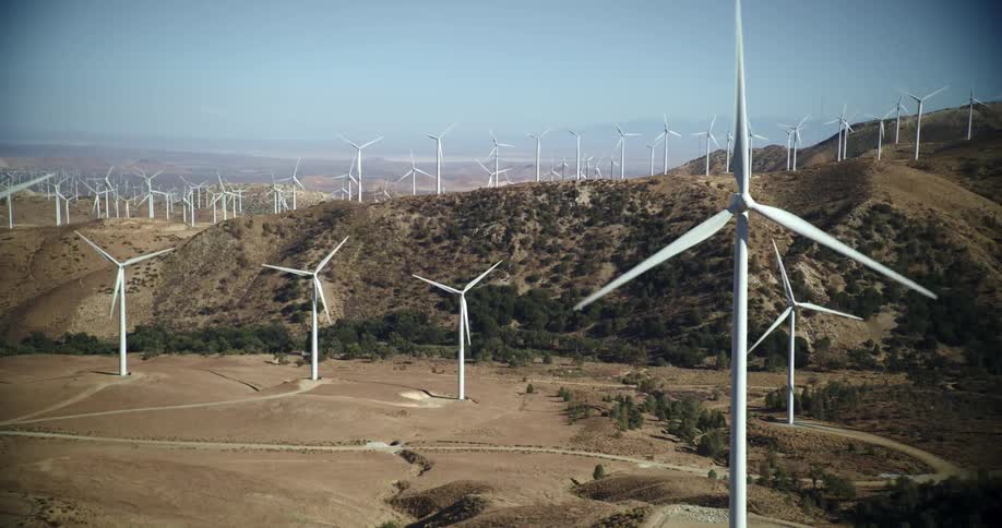 Aerial view of wind turbines running on wind farm in the hills