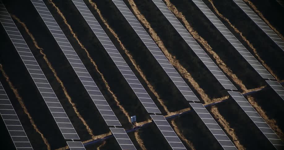 Aerial view of rows of solar panels on a solar farm in the desert