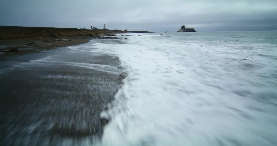 Waves roll in over a beach under a dark cloudy sky