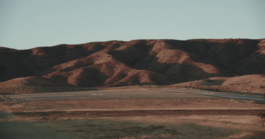 Solar panels sit in the desert near sand dunes