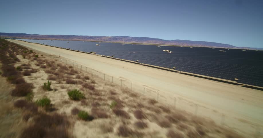 Aerial view of a large solar farm in the desert close to a road at daytime