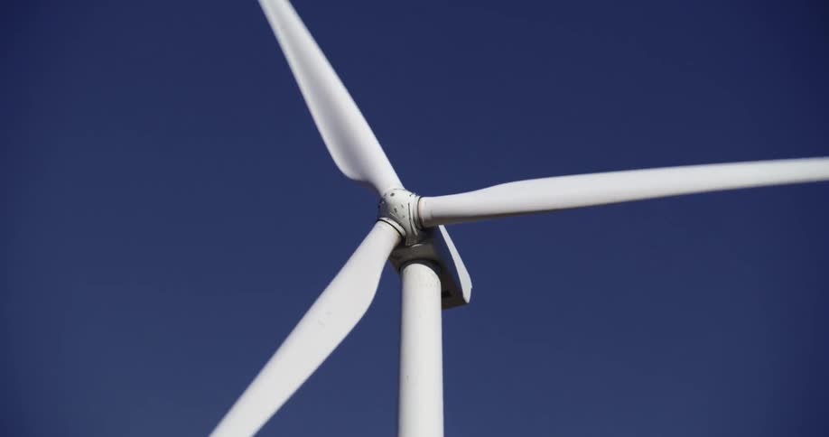 A wind turbine is spinning in a deep blue sky