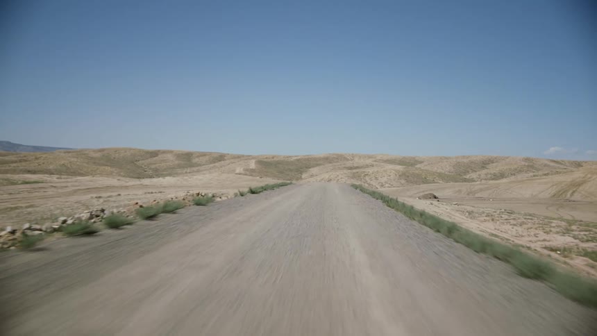 Traveling on a dirt road in the desert with mountains in the distance