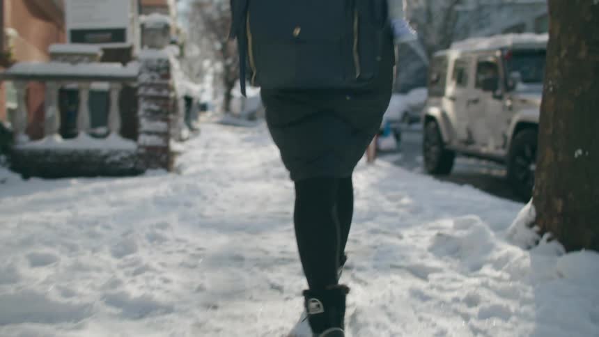 A woman walking in the snow with a baby