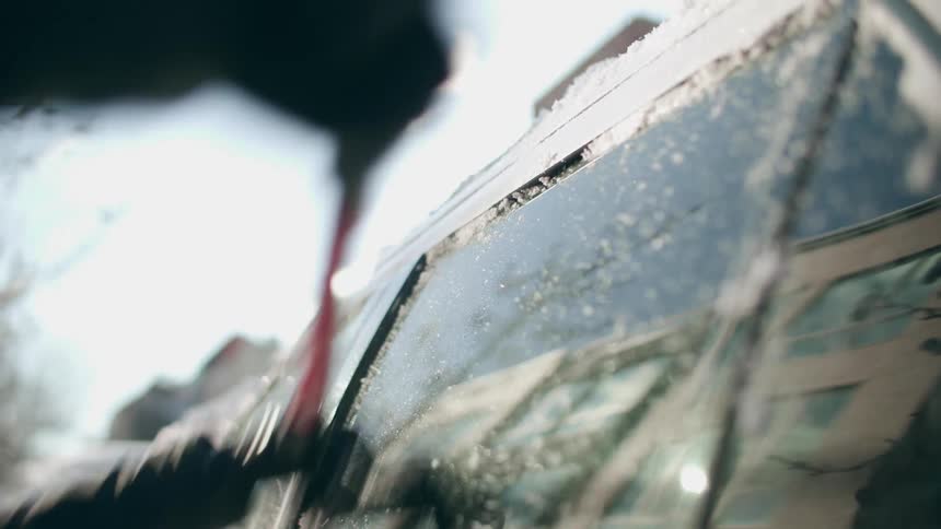 A person scraping ice off of their car