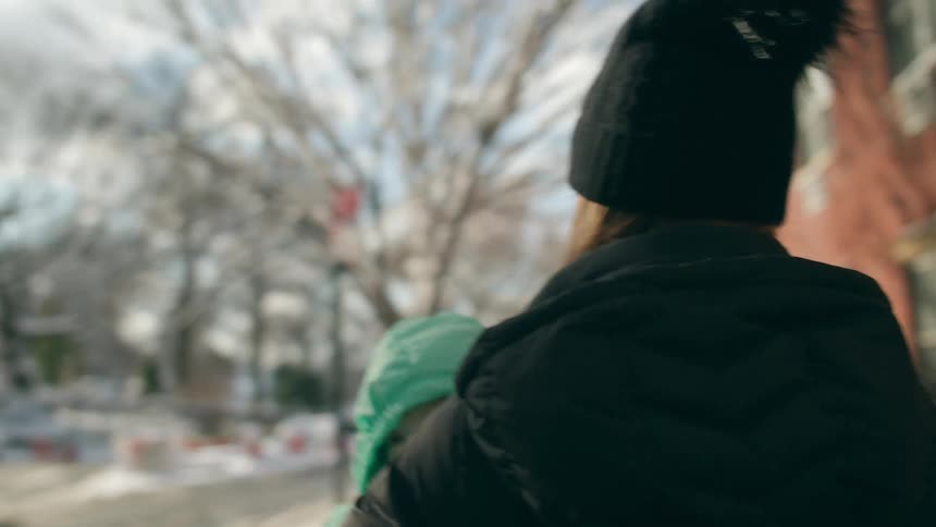 Mother carries a baby on the city street at winter