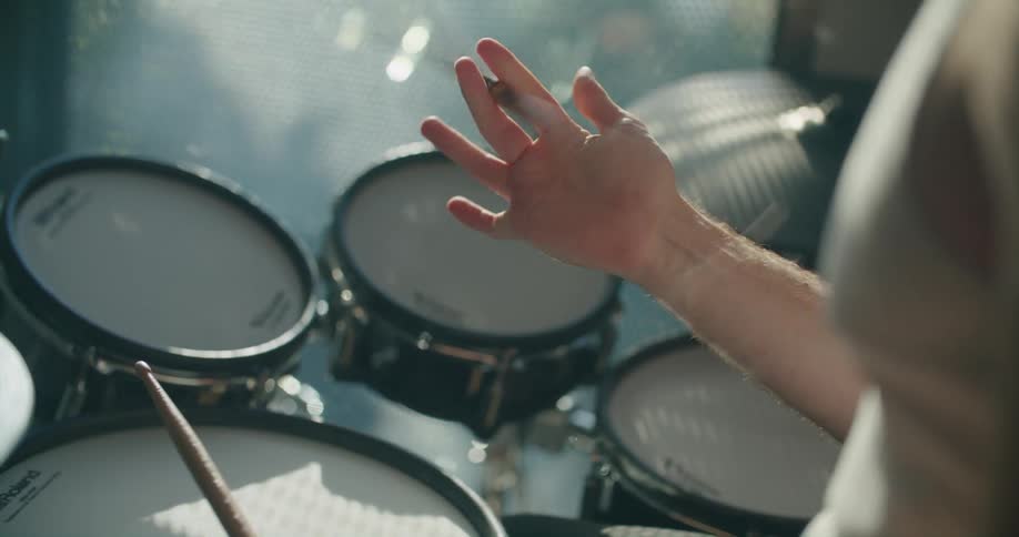 Man twirling drumstick with fingers above a set of drums